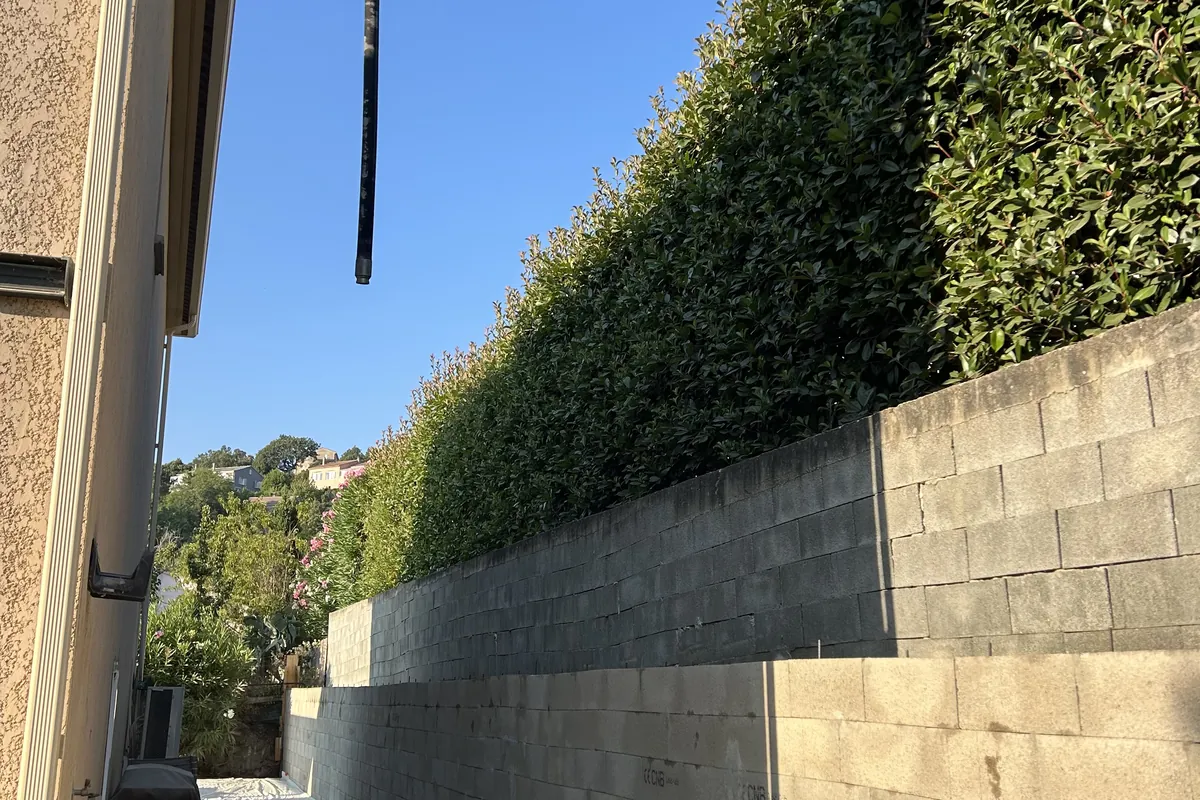 Mur de soutènement en blocs à bancher le long de la haie, flèche de la pompe à béton, Murato